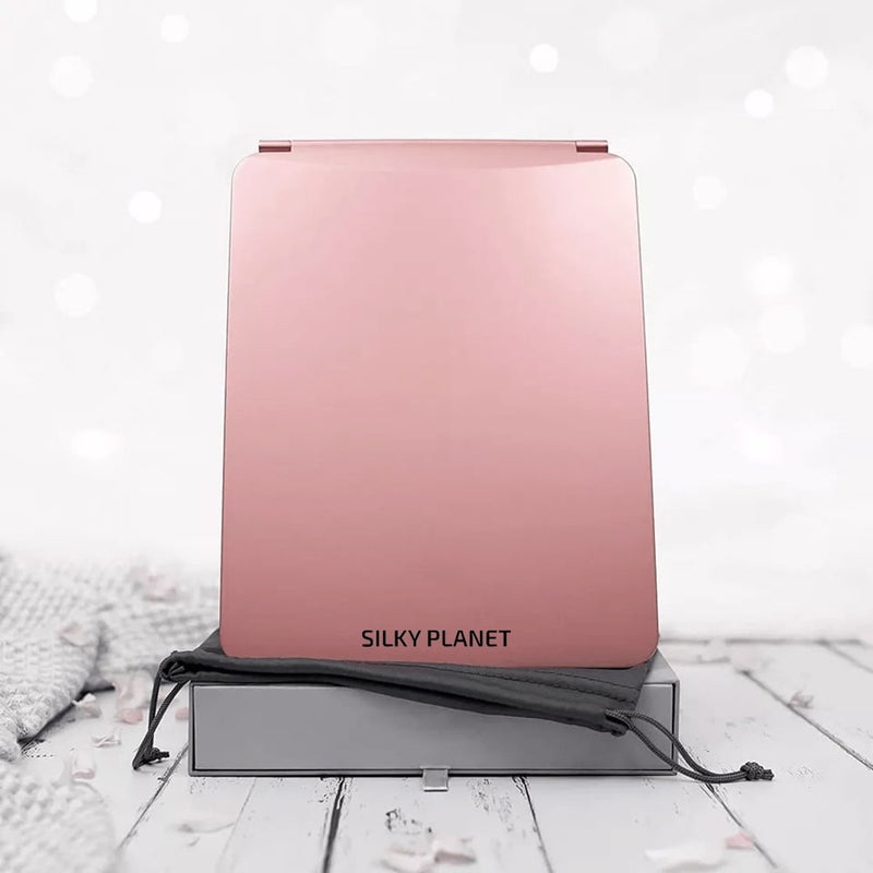 Hopfälld Silky Planet sminkspegel i roséguld med logotyp, stående bredvid förvaringspåse.